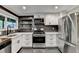 Modern kitchen boasts stainless steel appliances, floating shelves, and white cabinets at 975 Timber Lake Trl, Cumming, GA 30041