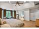 This spacious main bedroom features large windows, seating area, a view of the ensuite bath, and a lighted ceiling fan at 7249 Village Creek Trce, Atlanta, GA 30328
