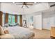 This spacious main bedroom features large windows, seating area, a view of the ensuite bath, and a lighted ceiling fan at 7249 Village Creek Trce, Atlanta, GA 30328