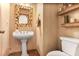 Charming powder room features a pedestal sink, decorative mirror, shelving, and elegant finishes at 7249 Village Creek Trce, Atlanta, GA 30328