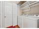Bright laundry room with a washer, dryer, floating shelves, white door, and red rug at 109 Windcroft Nw Cir, Acworth, GA 30101