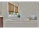Close-up of a bathroom jacuzzi tub beneath a window with bamboo shades and floral wallpaper at 1152 Ward Creek Sw Dr, Marietta, GA 30064