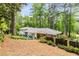 A charming backyard with lush trees surrounding a white home with an outdoor seating area at 504 Kingswood Nw Ln, Atlanta, GA 30305