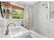 Bright bathroom featuring a pedestal sink, subway tile shower and a large window with natural light at 504 Kingswood Nw Ln, Atlanta, GA 30305