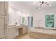 Bright bathroom featuring dual sinks, vanity with granite counters, and a large soaking tub with tiled surround at 160 Old Mill Ct, Fayetteville, GA 30214