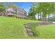 Picturesque view of a home with multiple decks, nestled on a lush green lawn overlooking the serene lake at 160 Old Mill Ct, Fayetteville, GA 30214