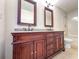 Bathroom with double sink vanity, granite countertop, dark wood cabinets, framed mirrors, and a tub in the background at 2160 Towne Manor Nw Dr, Kennesaw, GA 30144