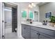 Bathroom featuring gray vanity, dual sinks, large mirror, and shower with patterned curtain at 5121 Hillside Haven Drive, Powder Springs, GA 30127