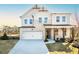 Charming two-story home with a white brick facade, a covered porch with stone pillars, and a two-car garage at 5121 Hillside Haven Drive, Powder Springs, GA 30127