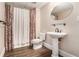 Bathroom with pedestal sink and patterned curtain surrounding the shower with brown wood-look flooring at 4910 Bucknell Trce, Cumming, GA 30028