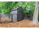 View of the wooden shed, surrounded by a black metal fence and lush greenery at 4910 Bucknell Trce, Cumming, GA 30028