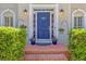 Inviting entryway with a blue front door, brick steps and colorful potted plants at 222 Mossy Pl, Alpharetta, GA 30005