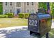 A quaint mailbox stands in front of a two-story home with a blue door and manicured landscaping at 222 Mossy Pl, Alpharetta, GA 30005