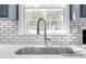 Close up of a stainless steel kitchen sink with gooseneck faucet, tile backsplash, and bright window at 222 Mossy Pl, Alpharetta, GA 30005