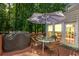 Outdoor patio with table, chairs, grill, and umbrella overlooking wooded area at 222 Mossy Pl, Alpharetta, GA 30005