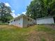 View of home's exterior with a grassy lawn, mature trees, and a storage building at 345 Forest Valley Rd, Lawrenceville, GA 30046