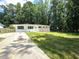 A charming white brick ranch-style home with a lush green front lawn, surrounded by mature trees at 345 Forest Valley Rd, Lawrenceville, GA 30046