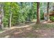 View of the wooded backyard, with retaining wall feature and rear house elevation to right at 3741 Windhurst Dr, Lilburn, GA 30047