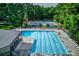 Community pool with marked swim lanes surrounded by mature trees, lounge chairs, and nearby tennis courts at 3741 Windhurst Dr, Lilburn, GA 30047