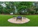 Fire pit area with stone surround and seating in a green backyard at 4131 West Village Pkwy, Ellenwood, GA 30294
