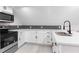 Kitchen features stainless appliances, double sink, herringbone backsplash, and white countertops at 4131 West Village Pkwy, Ellenwood, GA 30294