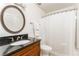 Bathroom with round mirror and dark countertop, featuring shower-tub combo with white shower curtain at 6204 Santa Fe Pkwy, Atlanta, GA 30350