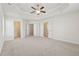 Large bedroom featuring a tray ceiling, fan, and multiple doorways leading to closets and bathrooms at 3182 Hartford Mill Pl, Duluth, GA 30097