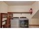 Laundry room including a Whirlpool washer and dryer set with storage shelves above, and stairs at 2584 Gravitt Rd, Duluth, GA 30096