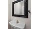 Powder room featuring pedestal sink with faucet and a black framed mirror at 3014 Volland Grove Trail, Lawrenceville, GA 30043