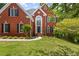 Charming two-story red brick home with lush green lawn and mature trees at 3014 Volland Grove Trail, Lawrenceville, GA 30043