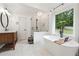 Bright bathroom with a freestanding tub, glass shower, wood vanity, and view of the backyard at 9545 Kingston Crossing Cir, Alpharetta, GA 30022