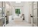 Elegant bathroom featuring a soaking tub, white tile floors, and a separate glass-enclosed shower at 9545 Kingston Crossing Cir, Alpharetta, GA 30022