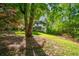 Lush backyard with a view of the house, featuring mature trees providing shade and privacy at 11950 Wildwood Springs Dr, Roswell, GA 30075