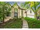 Charming two-story home with stone stairs and lush landscaping on a sunny day at 11950 Wildwood Springs Dr, Roswell, GA 30075