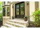 Elegant front door with stone steps, potted plants, and exterior sconces at 11950 Wildwood Springs Dr, Roswell, GA 30075