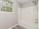 Clean bathroom with a shower-tub, new flooring, a bright window, and neutral colors at 5229 Kirk Dr, Atlanta, GA 30349