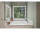 Relaxing bathtub area with a large window showcasing a private wooded view at 1243 Williamswood Pointe, Decatur, GA 30033