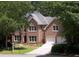 Charming two-story red brick home with a well-manicured lawn, beautiful trees and a driveway leading to a two-car garage at 1243 Williamswood Pointe, Decatur, GA 30033