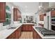 Open kitchen with stainless steel appliances, island cooktop, and views into the living area with hardwood flooring at 1243 Williamswood Pointe, Decatur, GA 30033