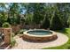 Stone hot tub with brick paver surround sits amongst professional landscaping and mature trees at 341 Carl Sanders Dr, Acworth, GA 30101