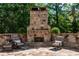 Backyard stone fireplace surrounded by seating and lush greenery at 341 Carl Sanders Dr, Acworth, GA 30101