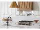 Close-up of kitchen showcasing countertops, modern faucet, gas range, and custom range hood at 7460 Trotting Trl, Cumming, GA 30040