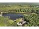 An aerial view showcases the house and surrounding forest alongside a pristine lake at 4095 E Highway 166 Hwy, Carrollton, GA 30116