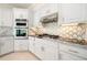 Close-up of kitchen showcasing white cabinets, stainless steel appliances, and a unique backsplash design at 5360 Northwater Way, Duluth, GA 30097