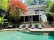 A beautiful backyard featuring a swimming pool, a spacious deck, and steps leading to a seating area with lounge chairs at 910 Kings Arms Way, Alpharetta, GA 30022