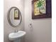 Stylish powder room with pedestal sink, decorative mirror and neutral paint at 1212 Lake Point Way, Suwanee, GA 30024