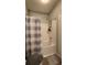 Neutral bathroom featuring a shower and tub combination behind a plaid shower curtain and gray rugs at 1250 Parkwood Cir # 2112, Atlanta, GA 30339
