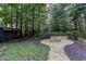 Backyard featuring stone firepit and walkway, plus storage shed, surrounded by lush trees and landscaping at 5010 Bonnie Way, Roswell, GA 30075