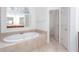 Bathroom with a large tub, tile floors, and a window with natural light at 5010 Bonnie Way, Roswell, GA 30075