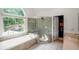 Main bathroom featuring a glass shower, soaking tub, white tile floors, large window, and walk-in closet at 103 Caracas Dr, Woodstock, GA 30188